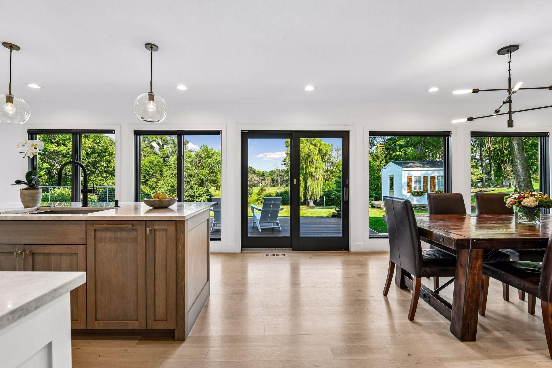 Adjacent to the kitchen, the dining room is surrounded by walls of windows that frame picturesque views of the wraparound deck and expansive backyard.