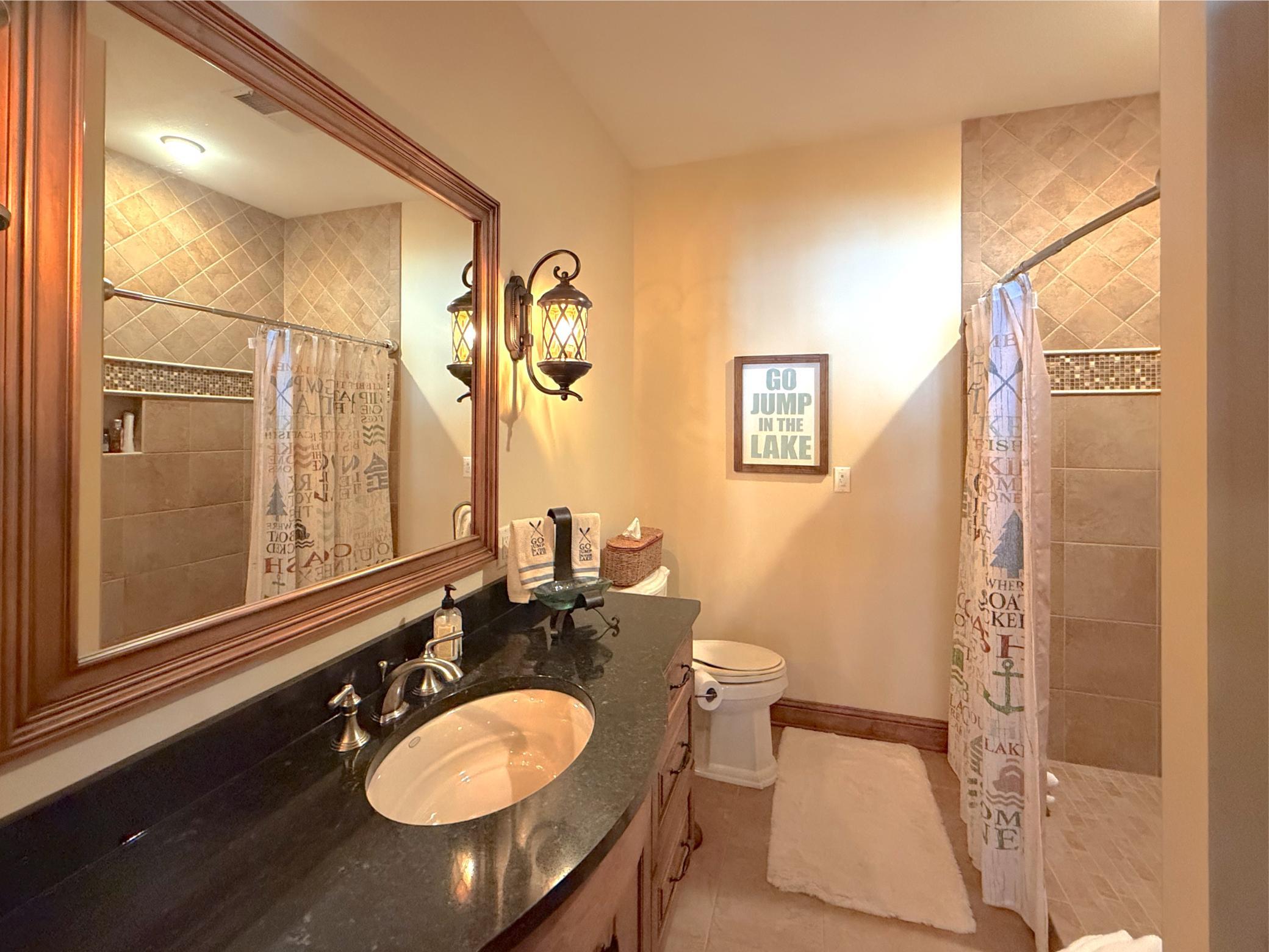 The lower-level ¾ bath features a beautifully tiled walk-in shower, granite countertops, and stylish finishes throughout.