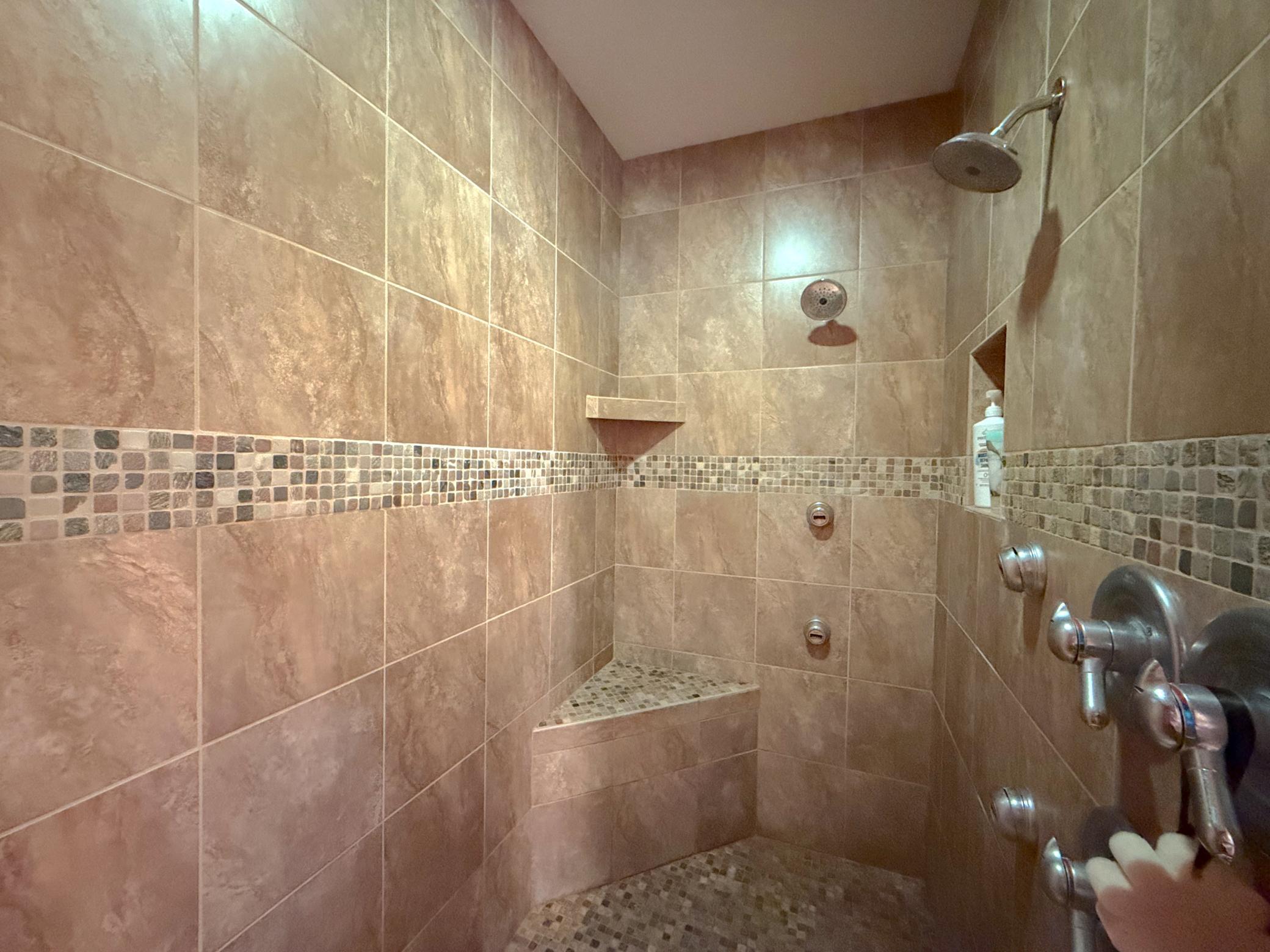 The expansive tiled walk-in shower adds a touch of spa-like luxury to this beautifully appointed primary bath.