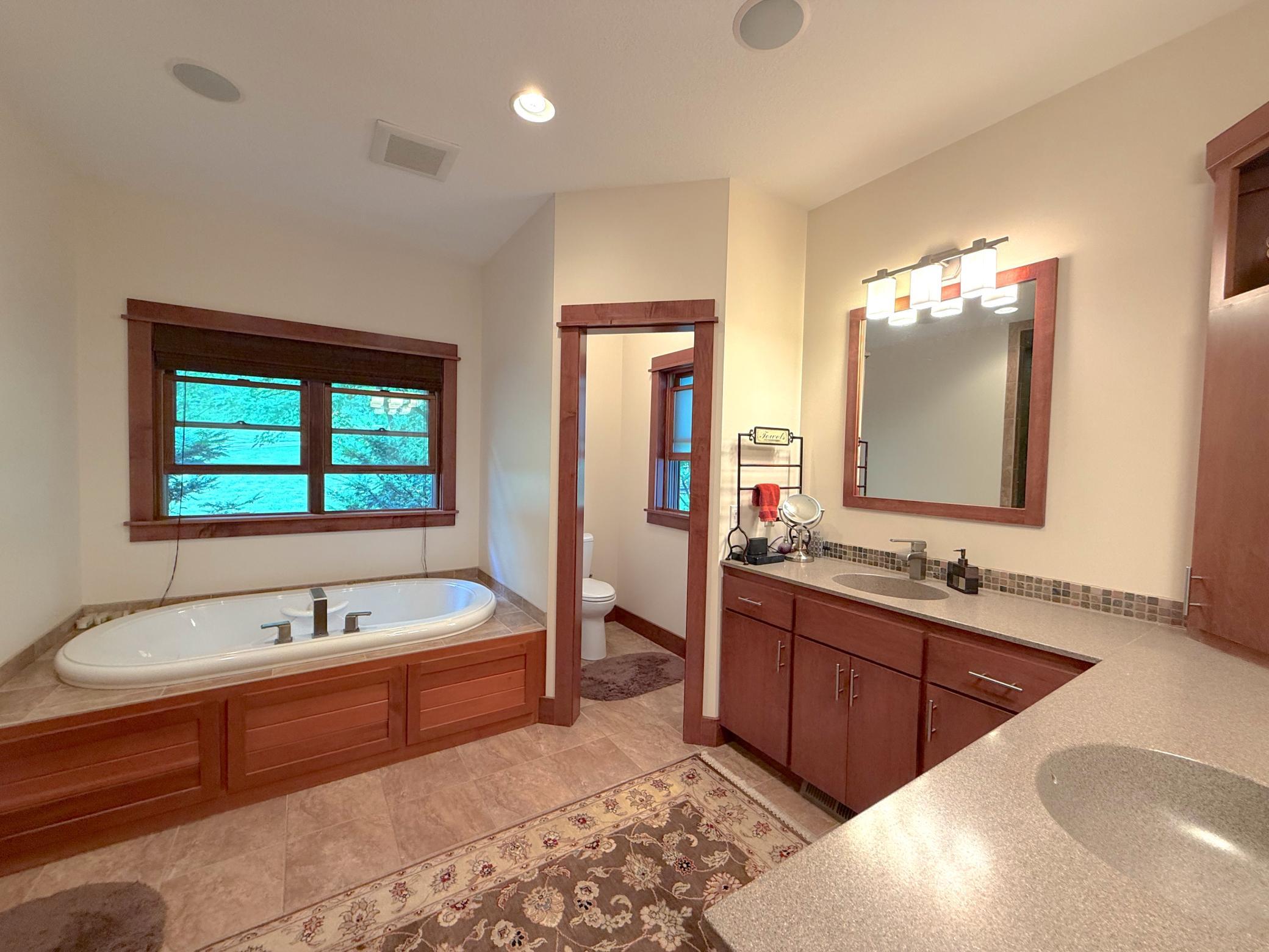 This expansive ensuite retreat combines comfort and convenience with dual sinks, a private water closet, walk in shower, and a tranquil soaking tub beneath picturesque windows.