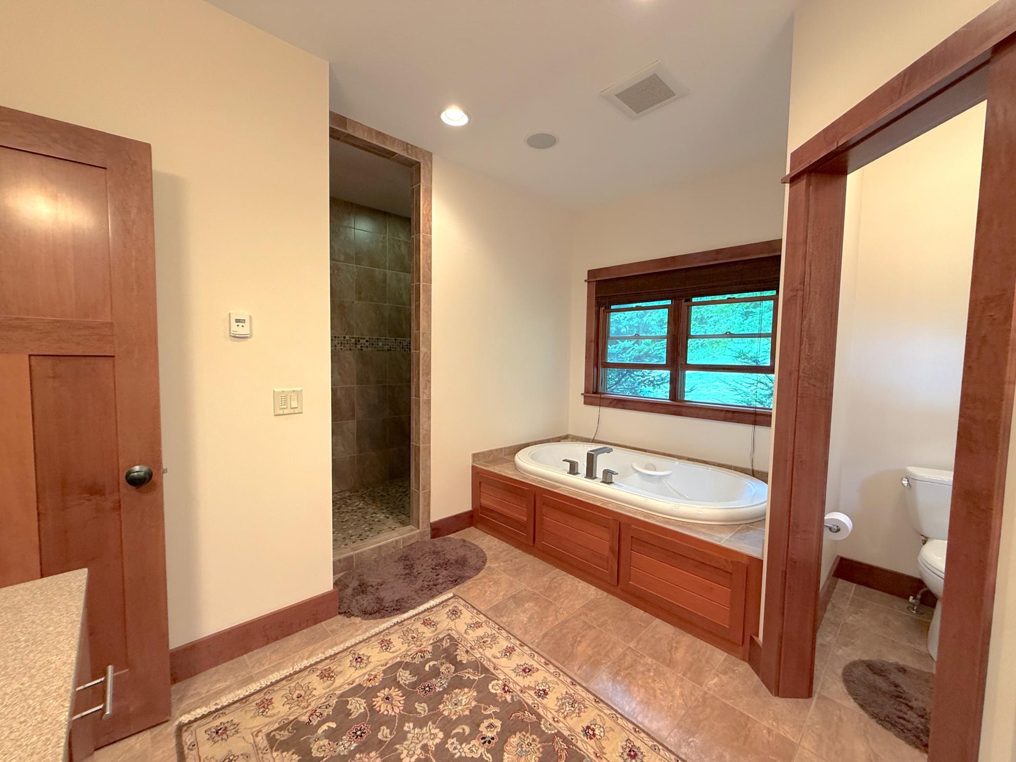 The luxurious primary bathroom showcases dual sinks, a private water closet, a walk-in shower, and a tranquil soaking tub, creating the ultimate owner's retreat.