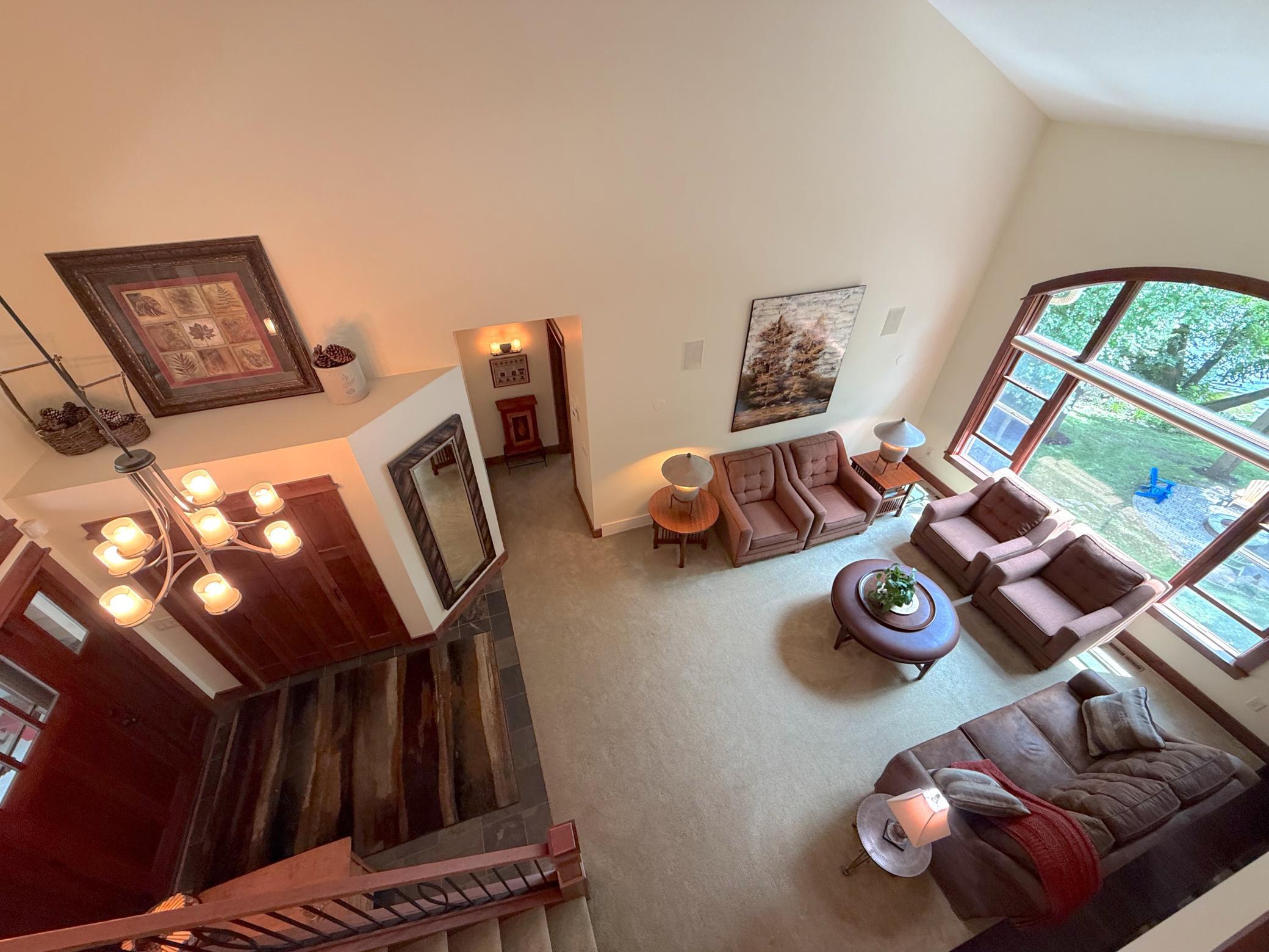 Relax in this spacious living room featuring soaring ceilings, expansive windows, and peaceful wooded views that bring the outdoors in.