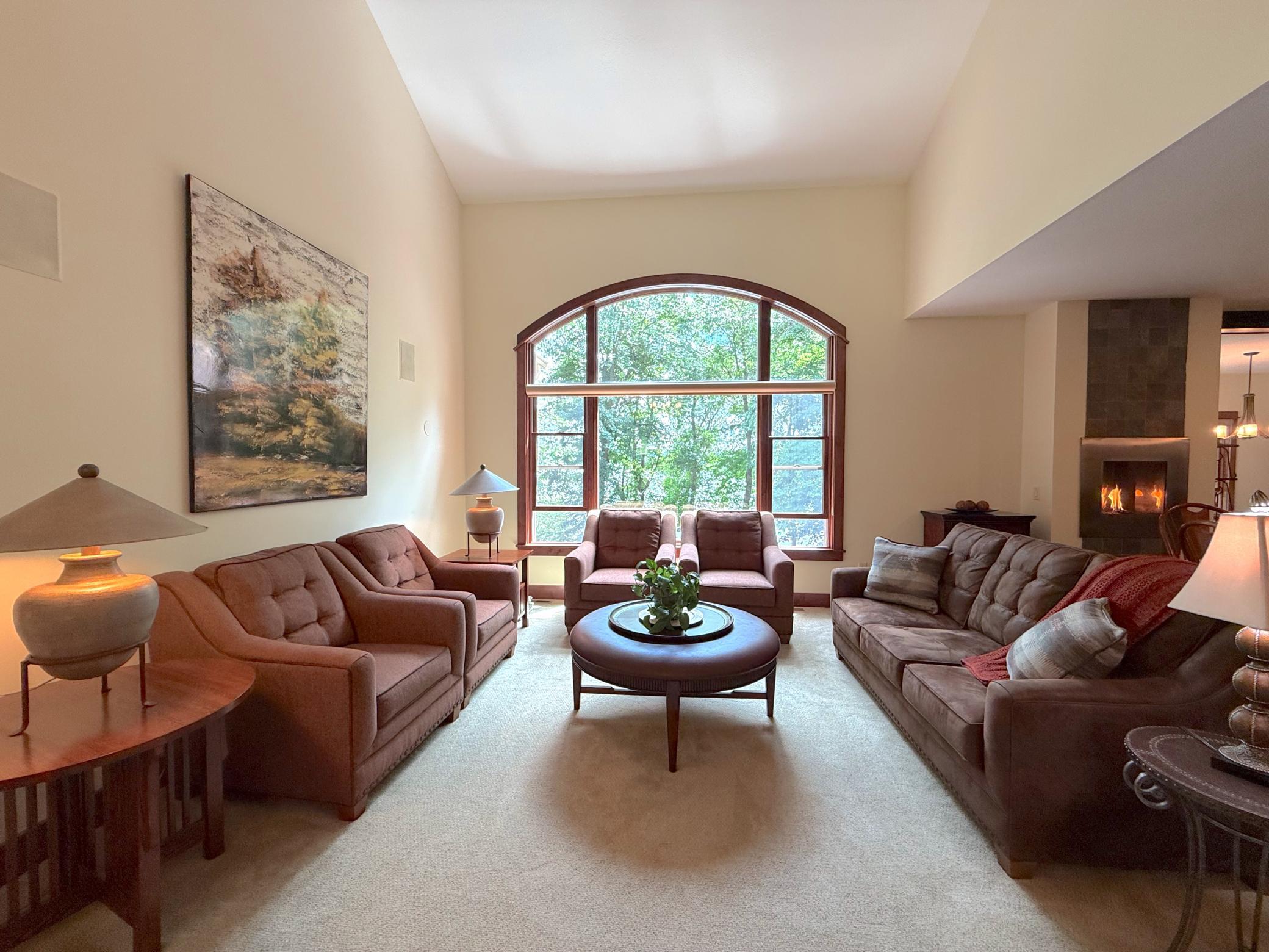 Gather with family and friends in this elegant living room highlighted by dramatic ceiling heights and a stunning picture window overlooking the surrounding landscape.