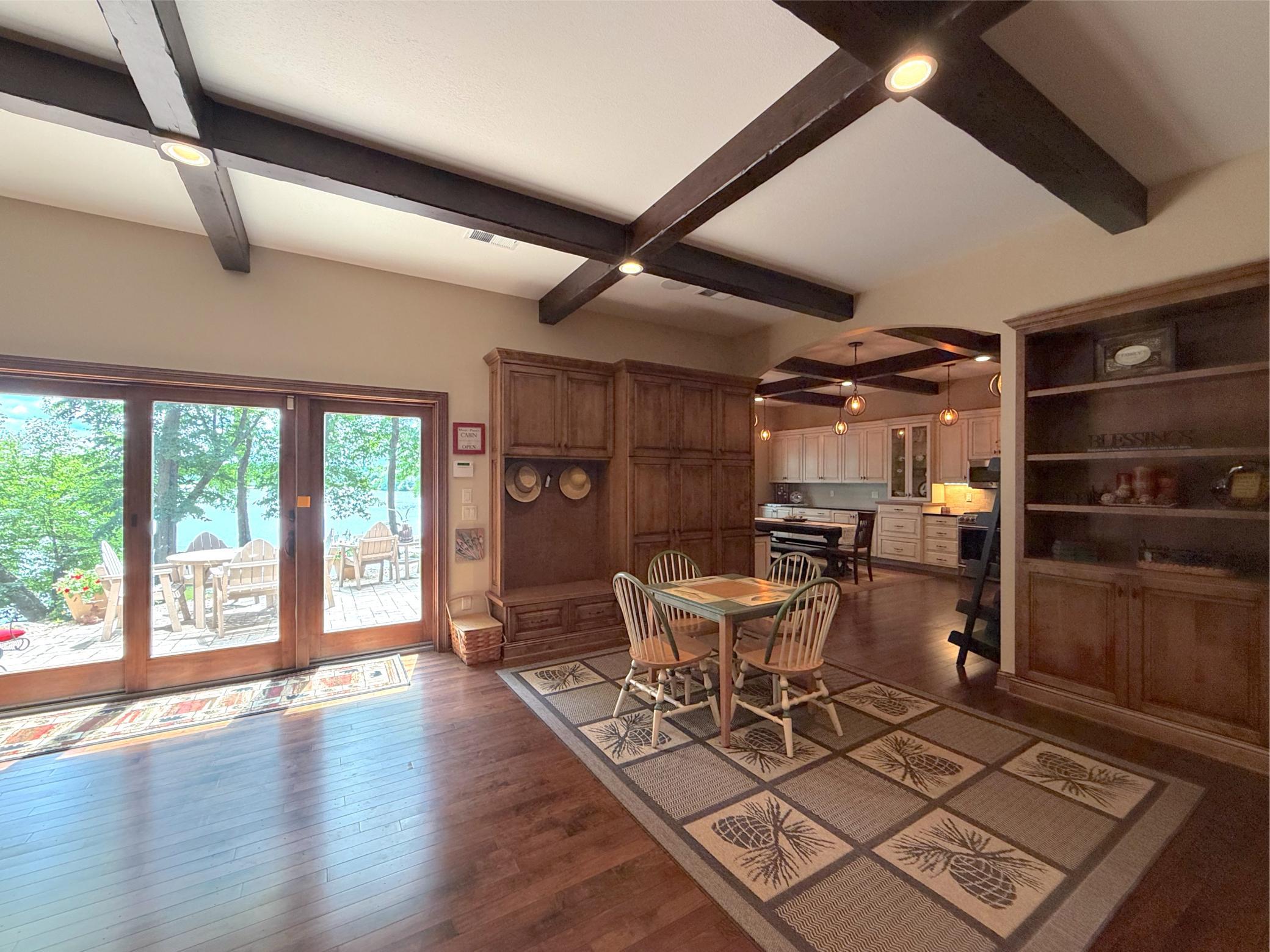 The walkout lower level features a spacious recreation area with custom built-ins, exposed beams, and direct access to the lakeside patio.