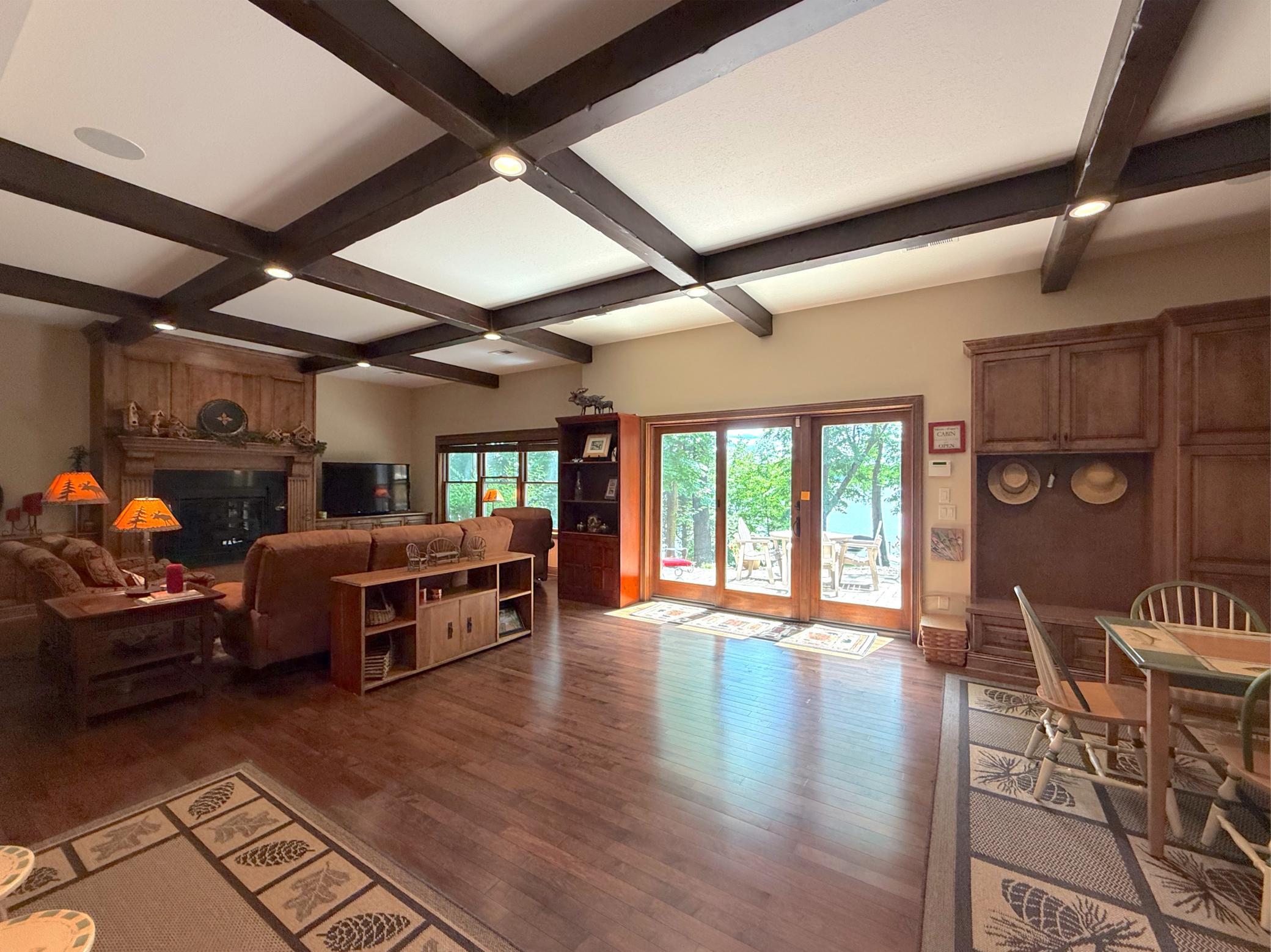 The expansive lower-level family room features a stunning 10 foot coffered ceiling, custom built-ins, and walkout access to the patio and lakefront beyond.