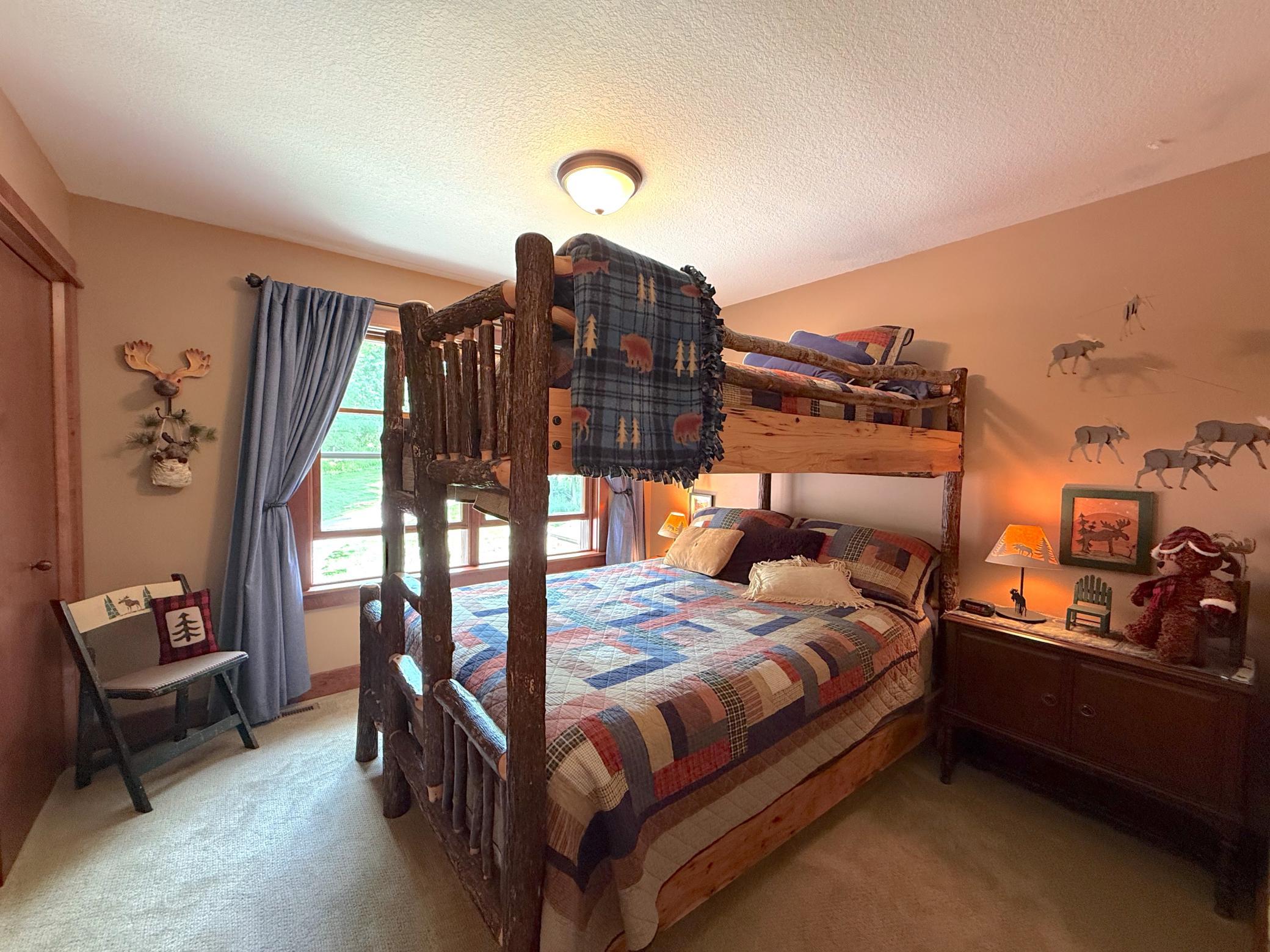 This inviting upper-level bedroom offers a warm, cabin-inspired ambiance and ample space for family and guests to relax.