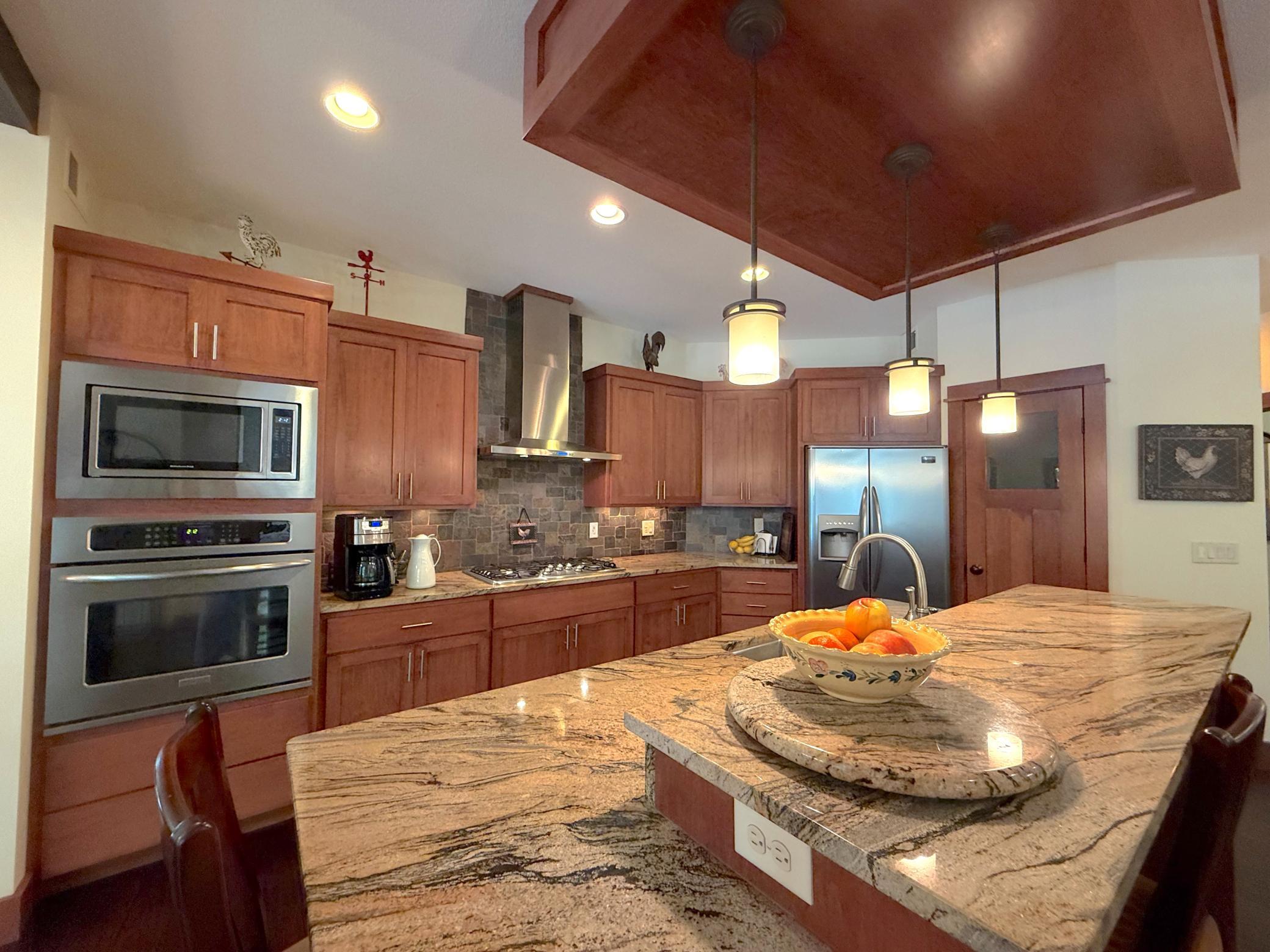 The chef's kitchen impresses with granite countertops, custom cabinetry, stainless steel appliances, and a spacious center island perfect for gathering.