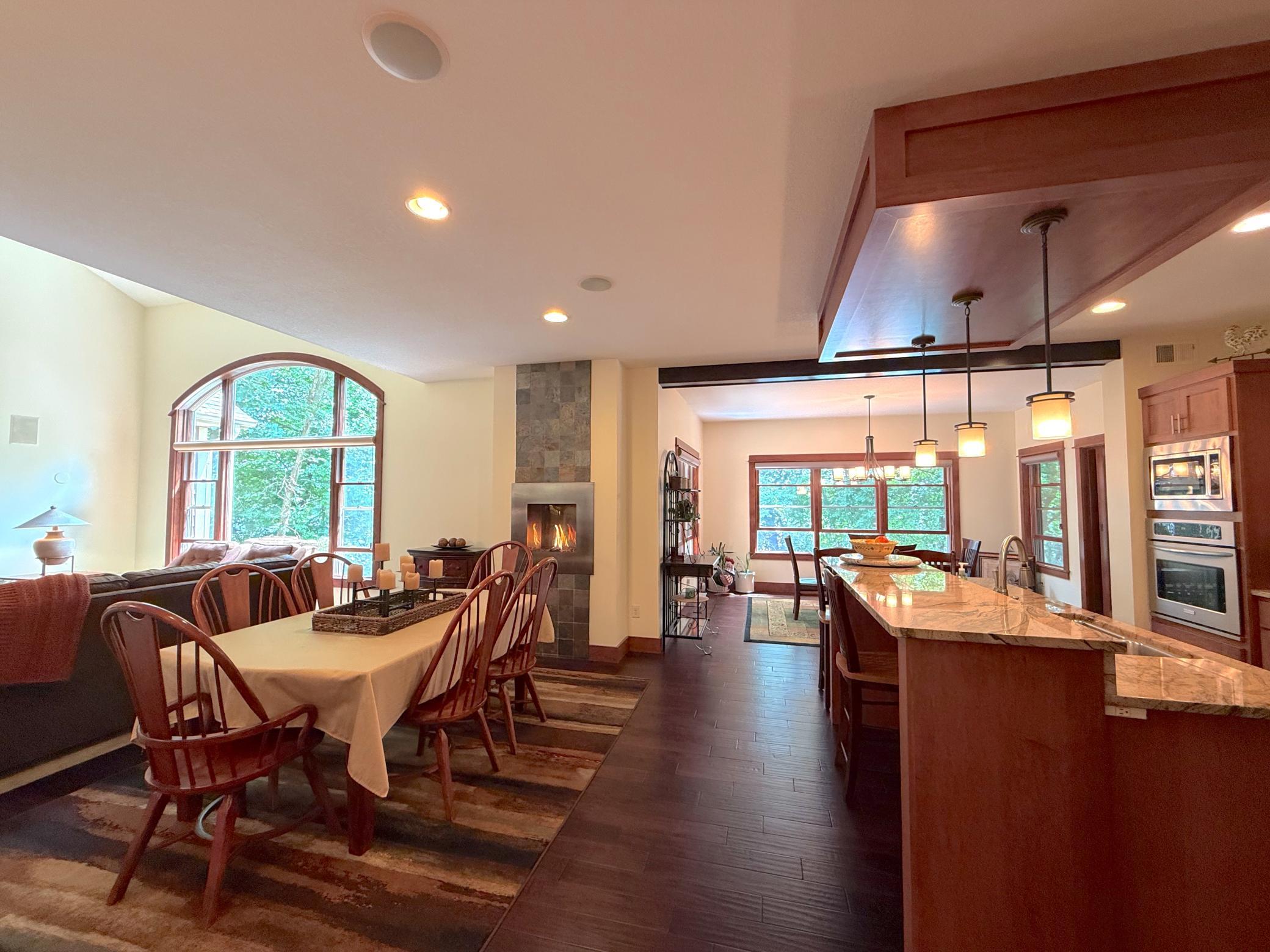 Gather with family and friends in this spacious open layout showcasing rich woodwork, stainless steel appliances, and a cozy fireplace that anchors the heart of the home.