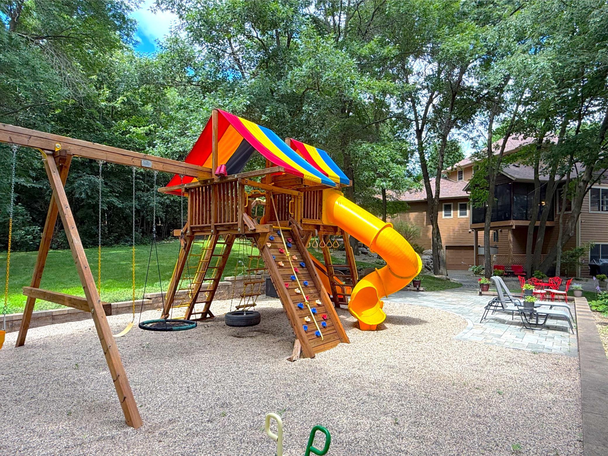 The beautifully landscaped patio area combines relaxation and recreation with ample seating, and a Rainbow® playset nestled among the mature trees.