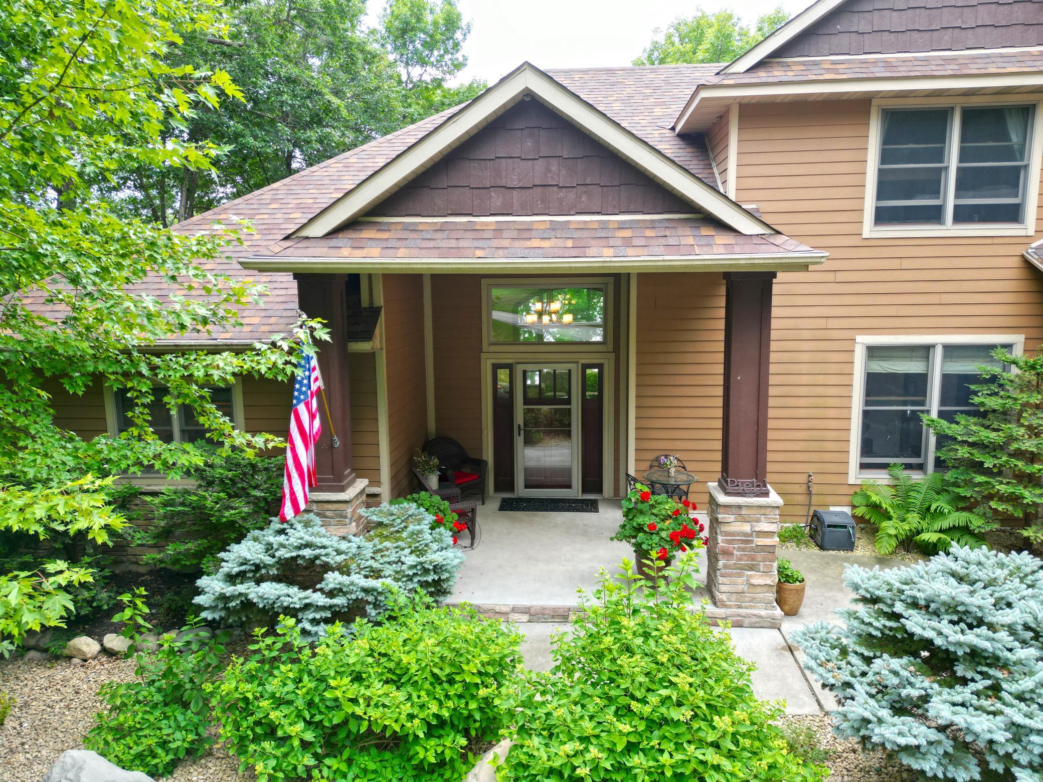 Welcome home, where guests are greeted by beautifully manicured mature landscaping and a welcoming covered front porch that creates a warm and inviting first impression.