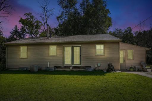 Charming single-level home with neutral siding, French doors, and large windowsâshown beautifully against a twilight sky.