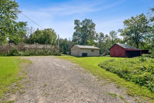 Detached garage with power and storage space, alongside the barn and long gravel driveway for ample parking.