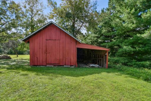 Rustic red barn with attached lean-to, providing storage or workshop potential.