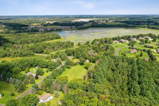Wide-angle aerial capturing the propertyâs proximity to scenic nature and nearby lake, adding to the tranquil lifestyle.