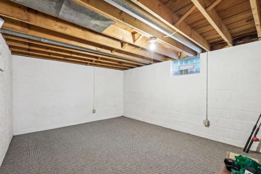 Spacious lower-level area with exposed beams and fresh white walls, ideal for a workshop, gym, or storage