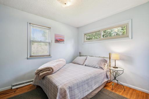 11_interior.Comfortable bedroom with hardwood flooring, light neutral walls, and two windows that create a bright and inviting retreat.