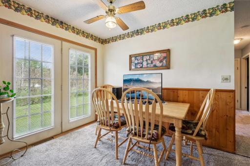 Cozy dining area with French doors opening to the backyard, ceiling fan, and warm wood accents.