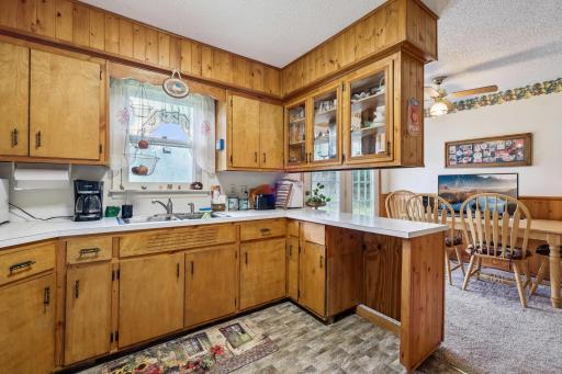 Bright kitchen with natural wood cabinetry, laminate countertops, and a window over the sink that overlooks the backyard.