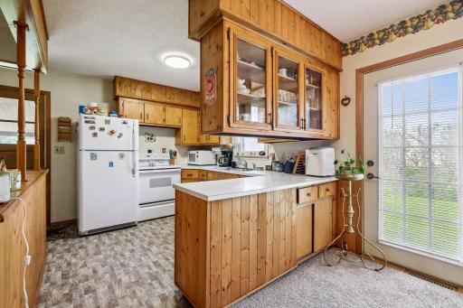 Functional kitchen with ample cabinet space, breakfast bar with glass-front upper cabinets, and direct access to the backyard through a glass-paned door.