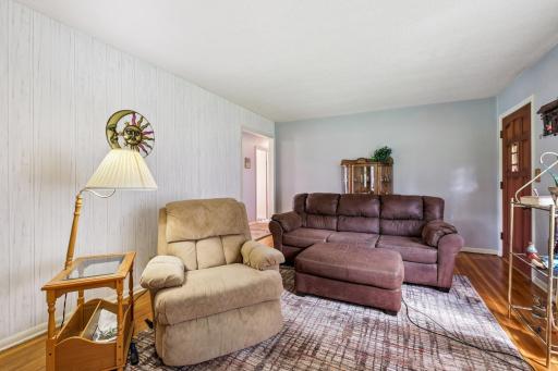 Spacious living room with large windows that fill the space with natural light, featuring hardwood floors and plenty of room for seating.