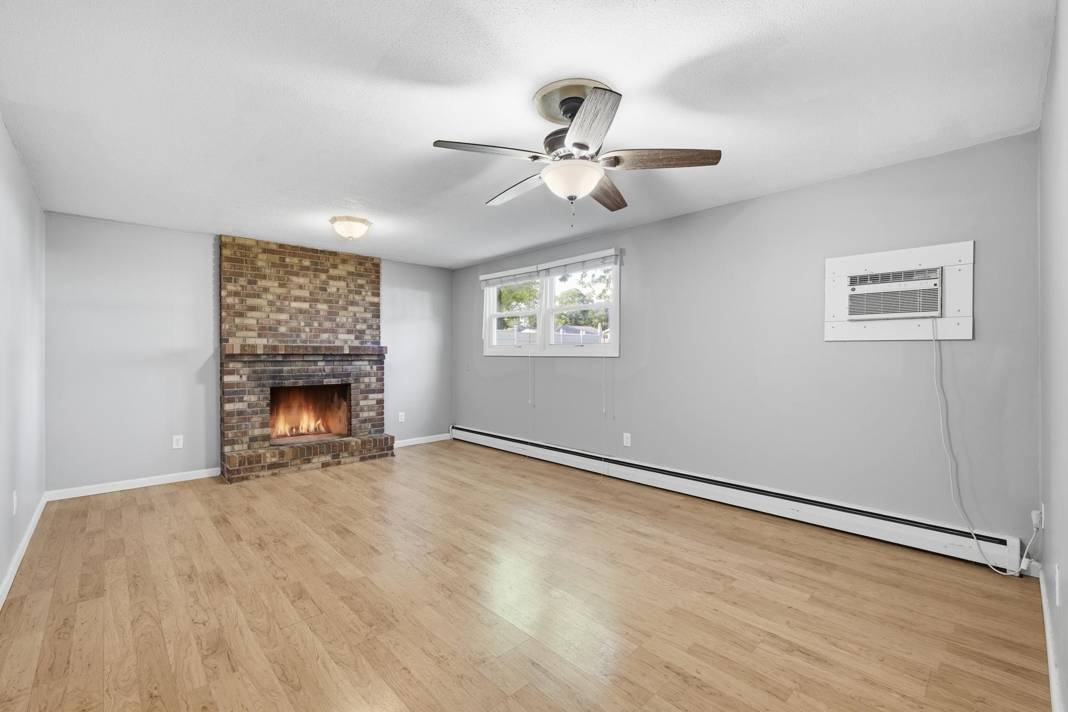 Cozy lower-level family room featuring a fireplace, durable laminate flooring, and a warm, inviting atmosphere perfect for relaxing or entertaining.