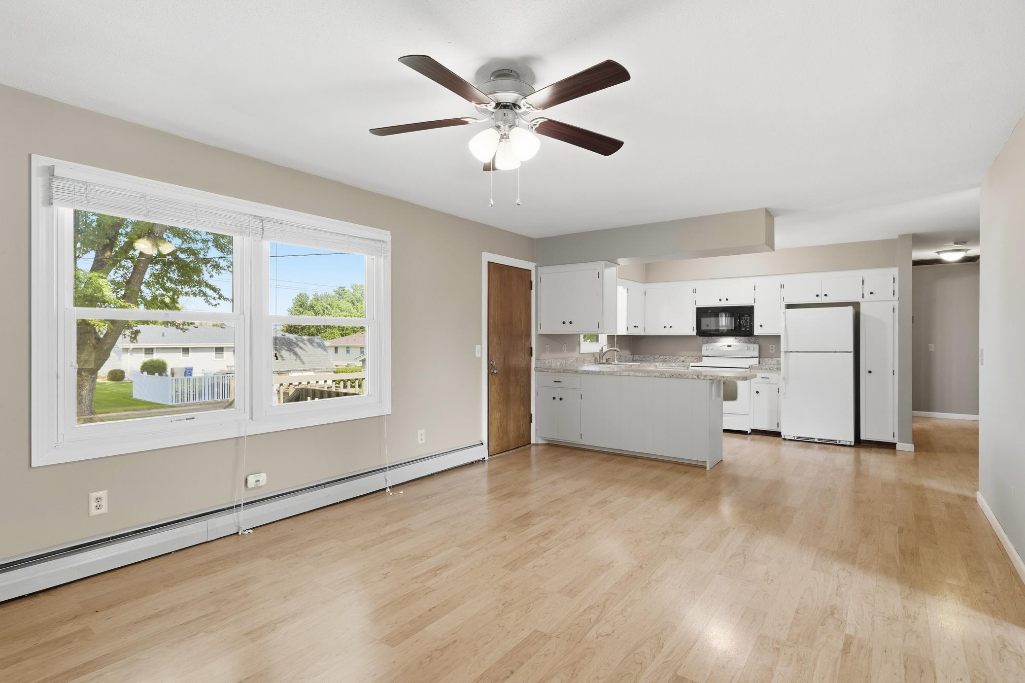 Open-concept kitchen and living area featuring large windows overlooking the backyard, with convenient access to the deck for seamless indoor-outdoor living and entertaining.