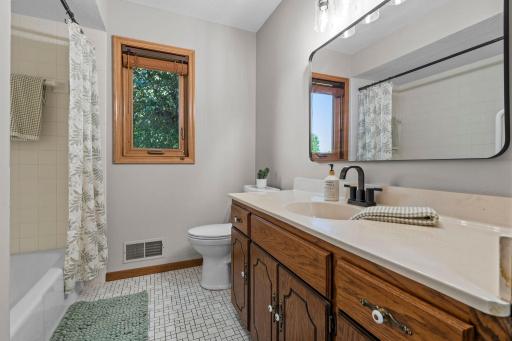 Bathroom tiled flooring, abundance of cabinetry and linen storage. Fresh paint, some updated fixtures, lighting, and bathroom mirrors.
