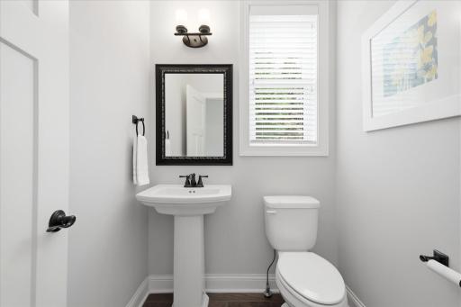 Convenient main-level half bath features a pedestal sink, updated lighting, and a bright window for added natural light.