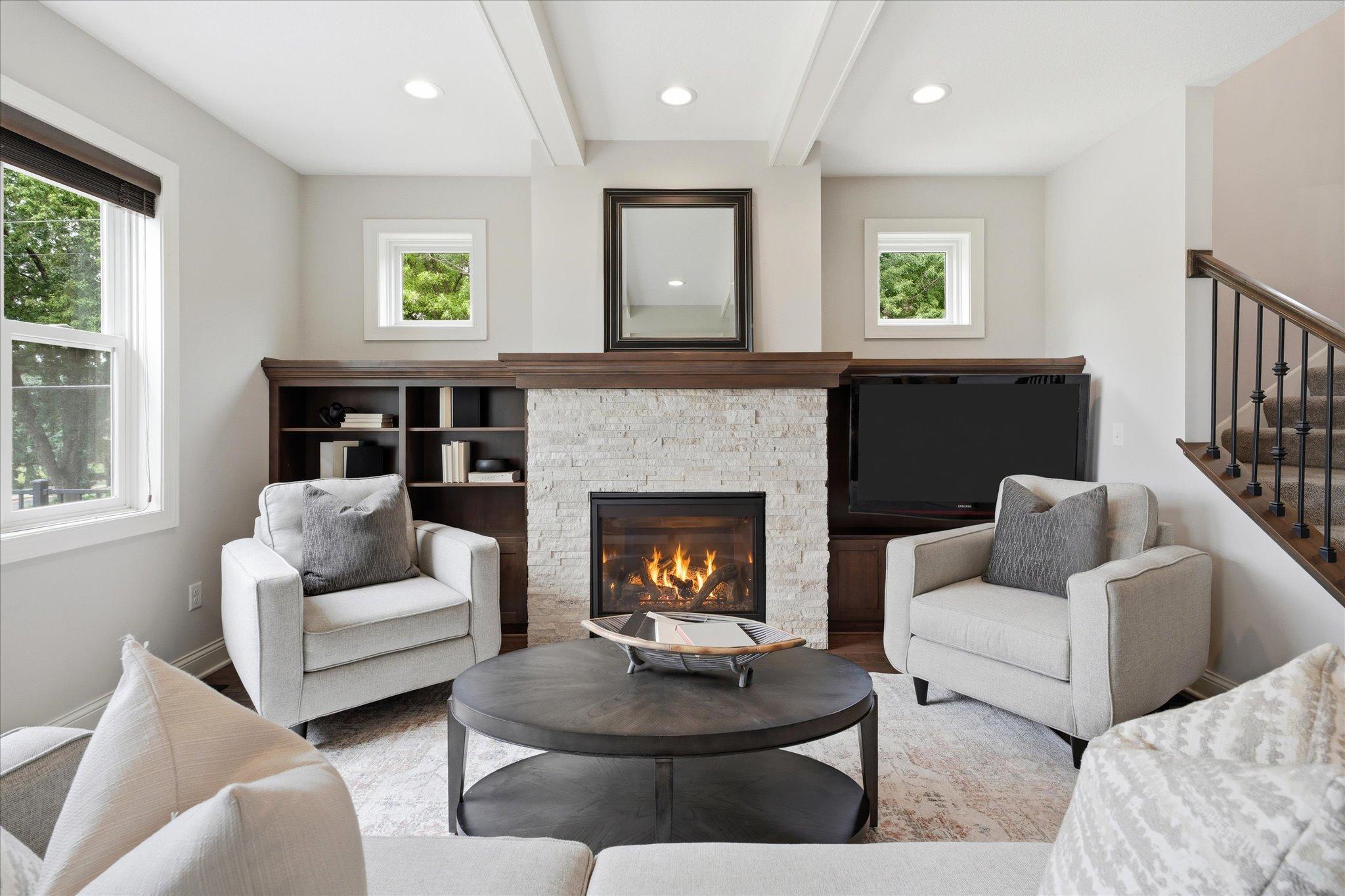 Beautiful gas fireplace serves as the centerpiece of the great room, complemented by custom built-ins, elegant millwork, and transom windows that add architectural charm.