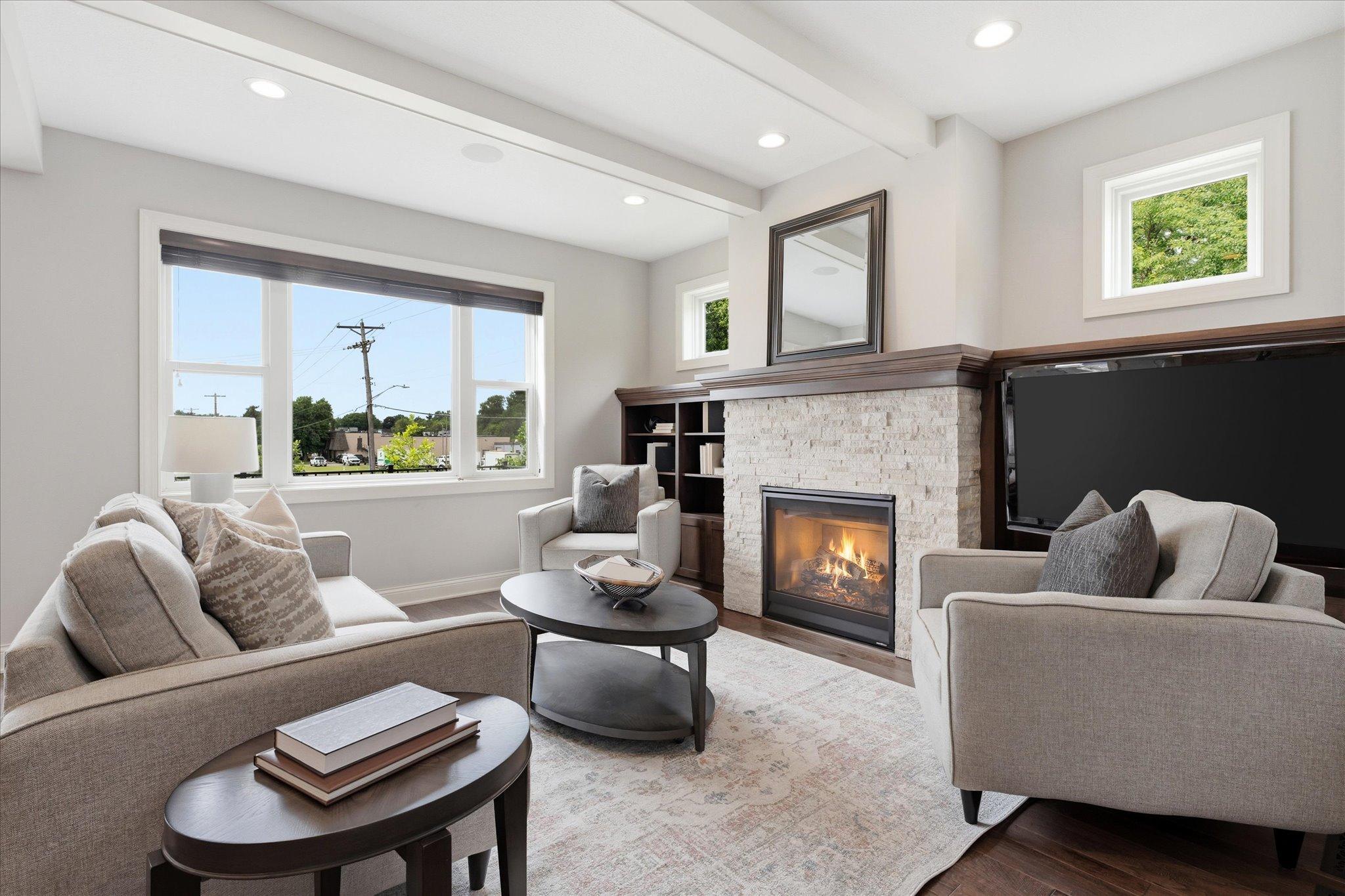 Spacious great room showcases a stunning floor-to-ceiling stone gas fireplace, custom built-in cabinetry, rich hardwood floors, and abundant natural light, creating the perfect gathering space.