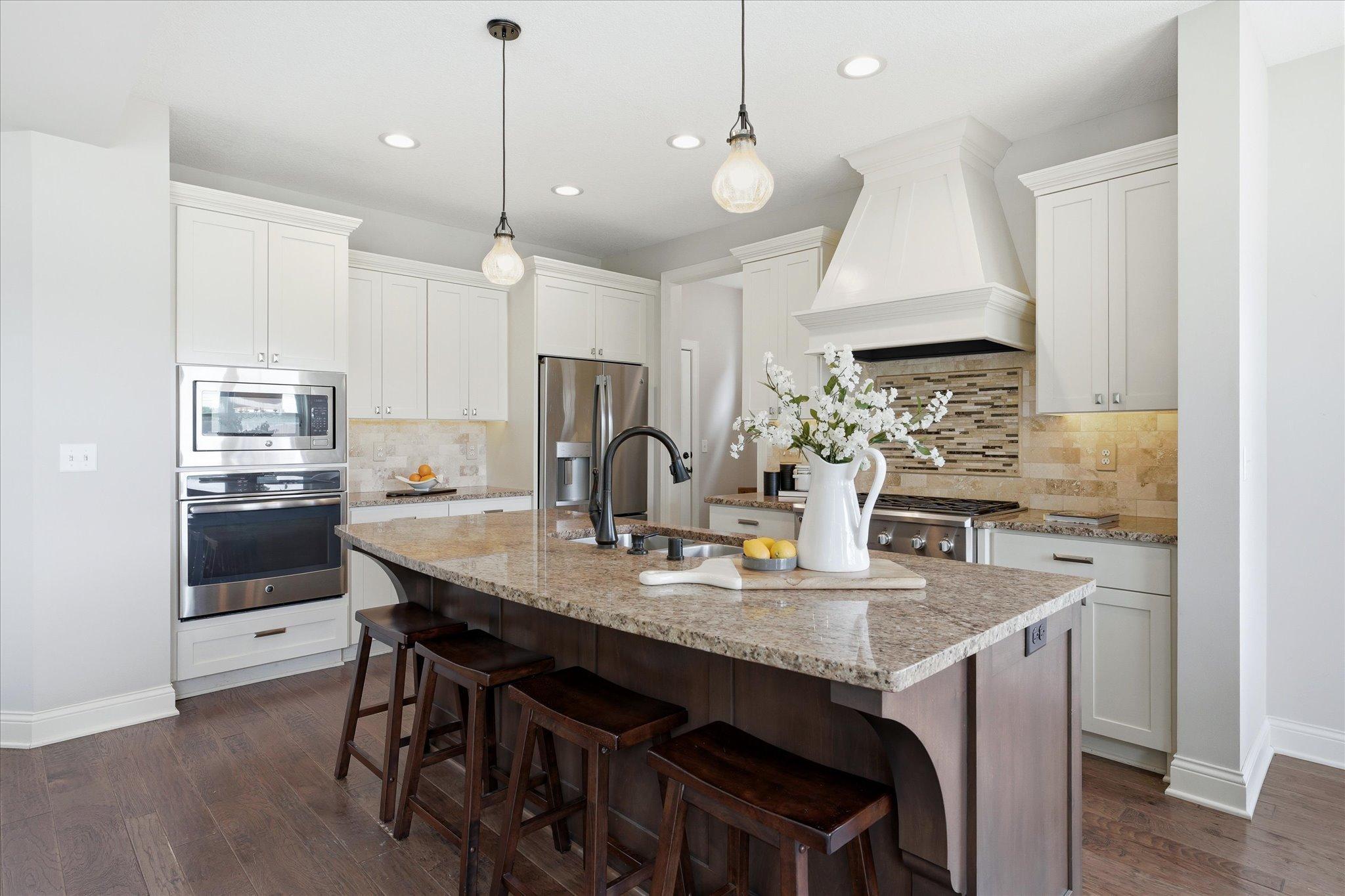 Gourmet kitchen features stainless steel appliances, double wall ovens, a gas cooktop, and a designer range hood.