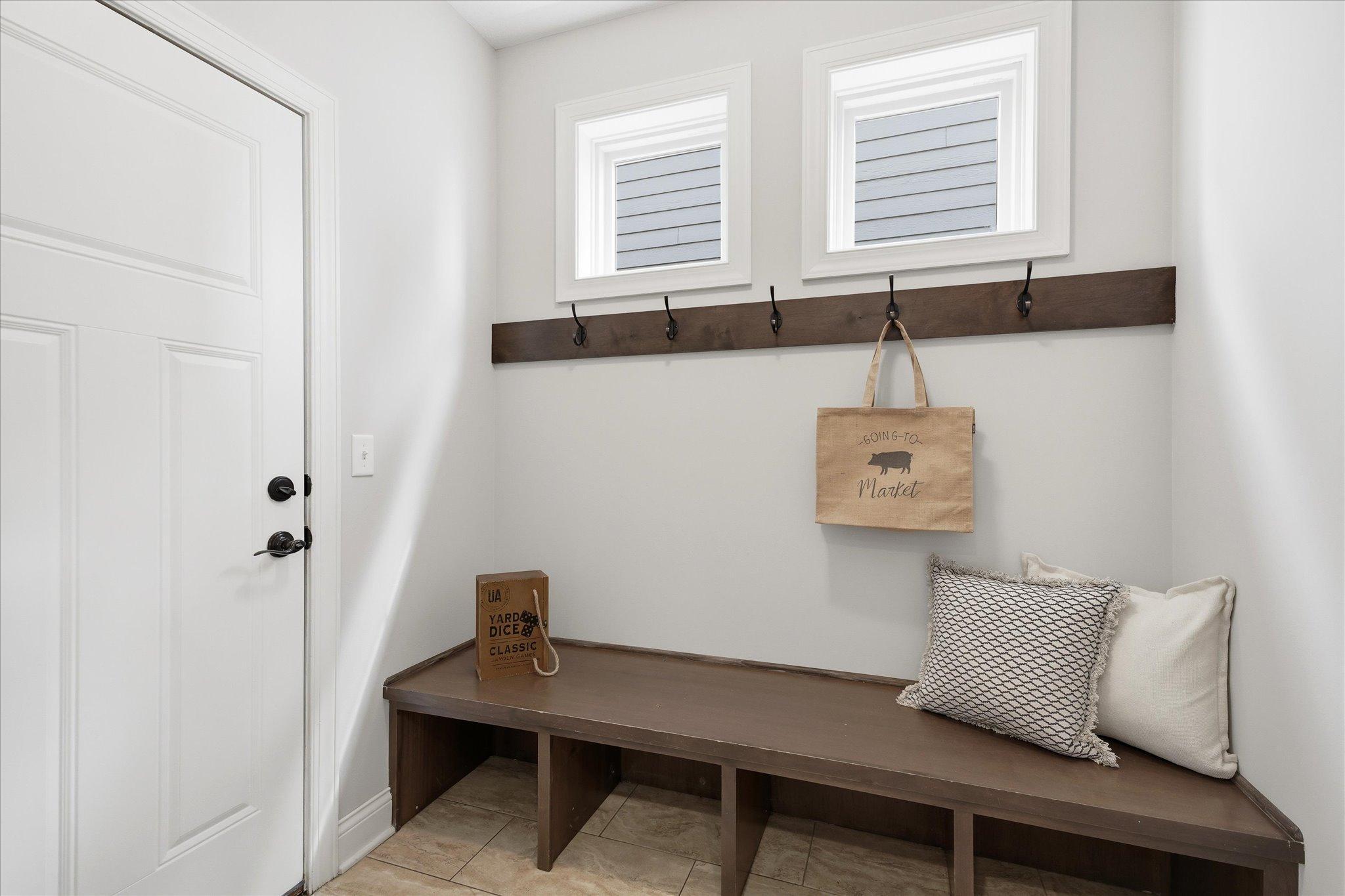 Functional mudroom features a built-in bench with cubbies and wall hooks, creating the perfect drop zone for coats, shoes, and everyday organization.