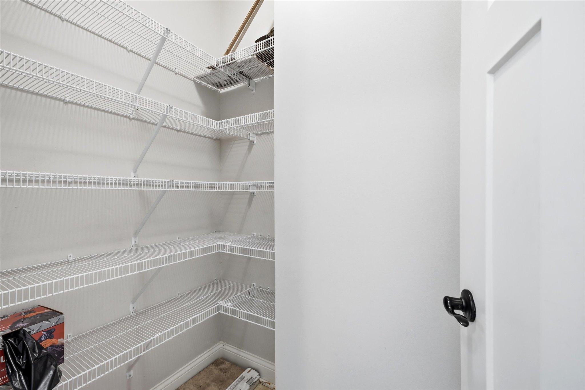 Spacious walk-in pantry offers extensive shelving and exceptional storage for groceries, small appliances, and kitchen essentials.
