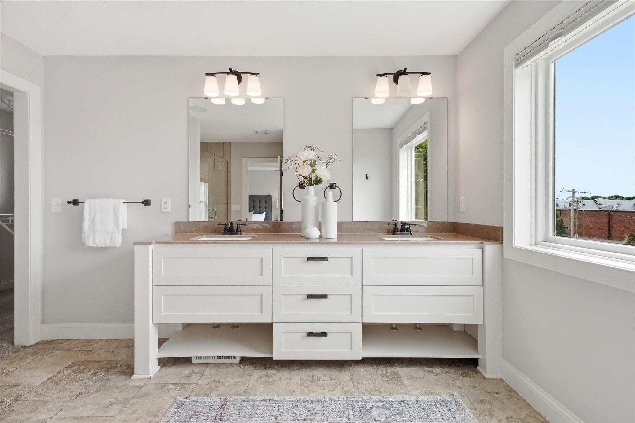 Spa-inspired primary bath features a dual-sink vanity with abundant storage, large mirrors, and plenty of natural light for everyday convenience.