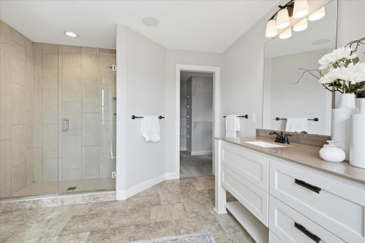 Oversized walk-in tile shower features frameless glass doors, and elegant tile surround.