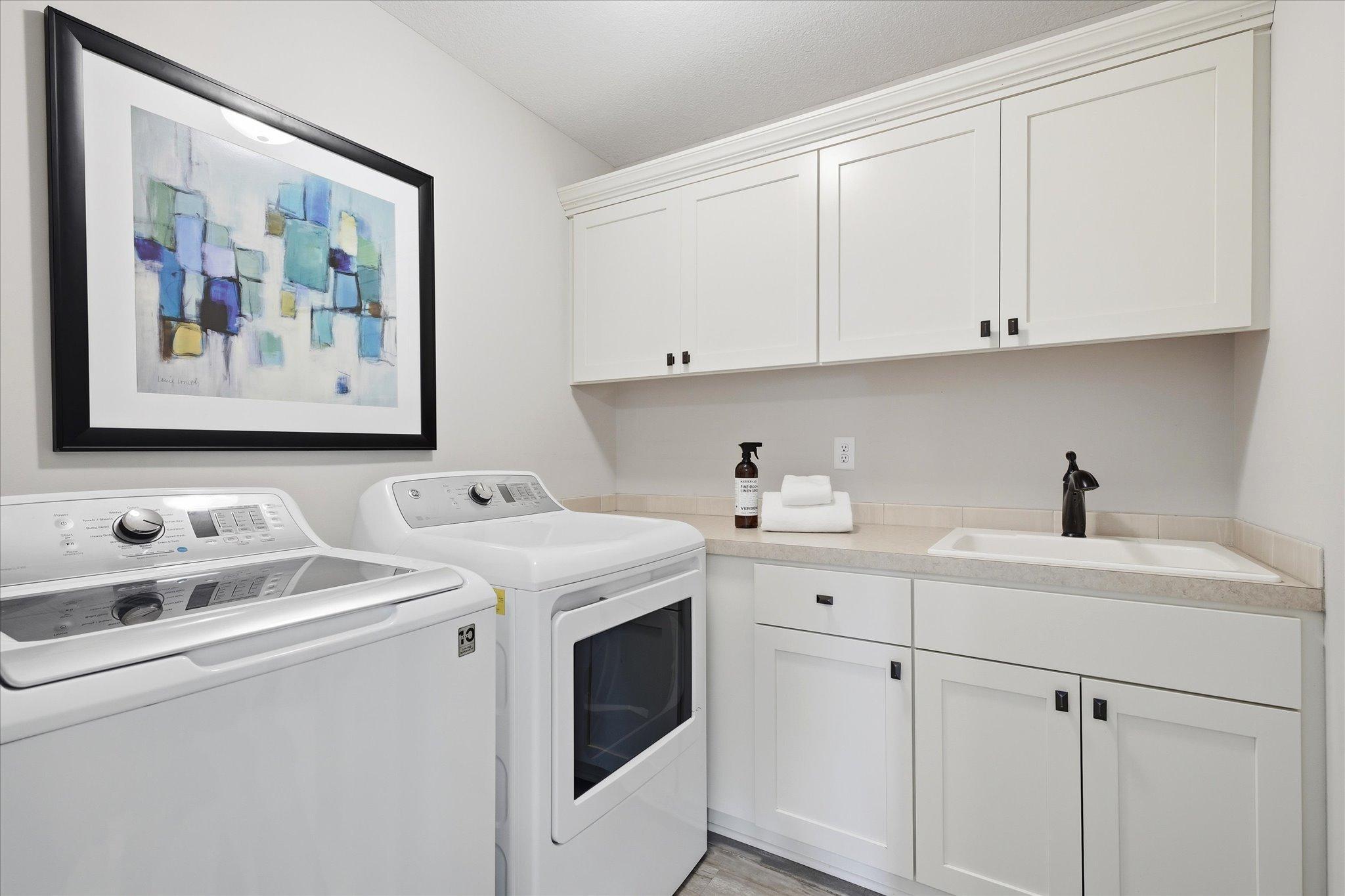 Convenient upper-level laundry room is thoughtfully located near all four bedrooms and features built-in cabinetry, folding counter, utility sink, and ample storage.