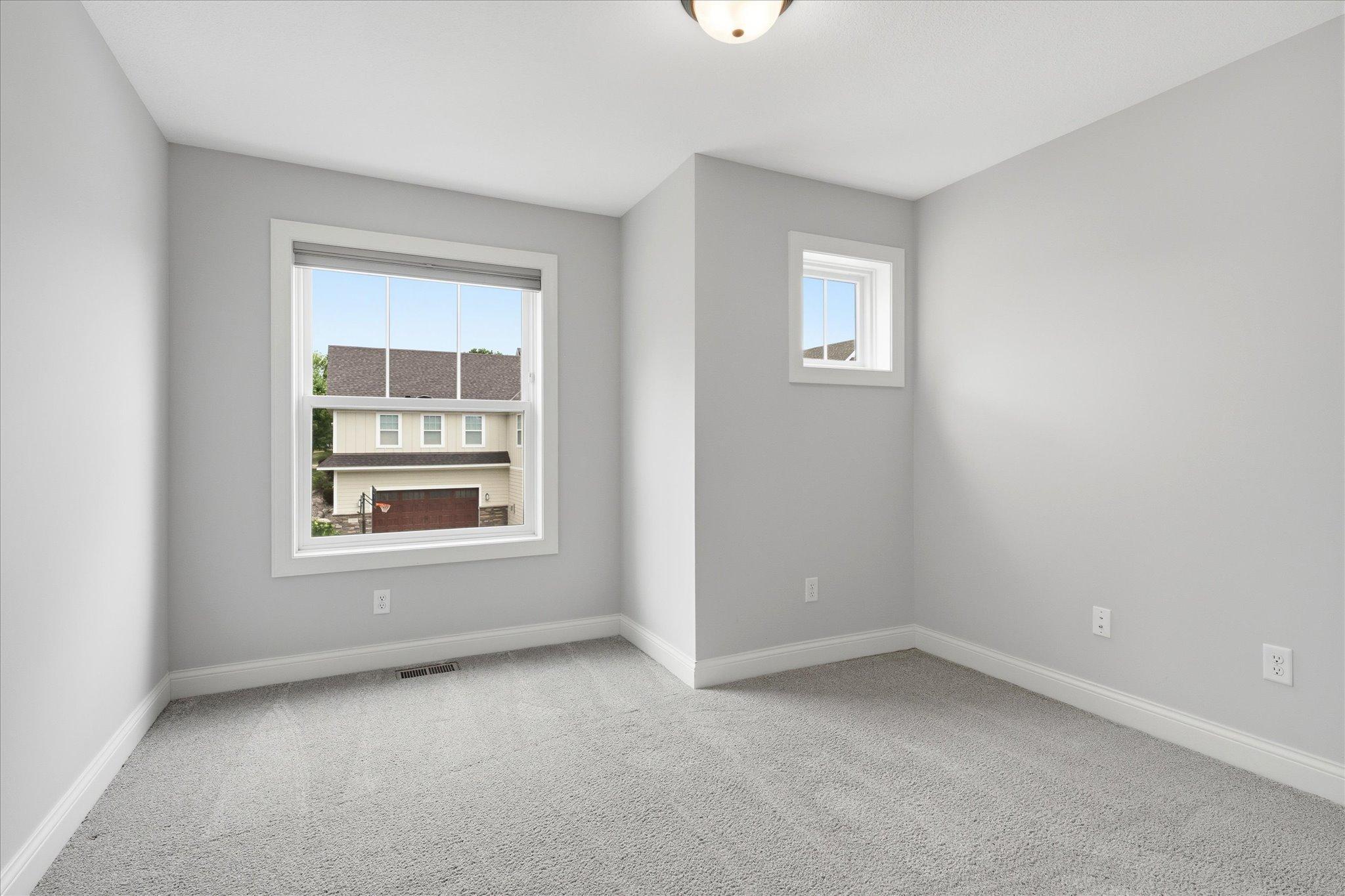 Spacious secondary bedroom offers plush carpeting, abundant natural light, and a generous layout.