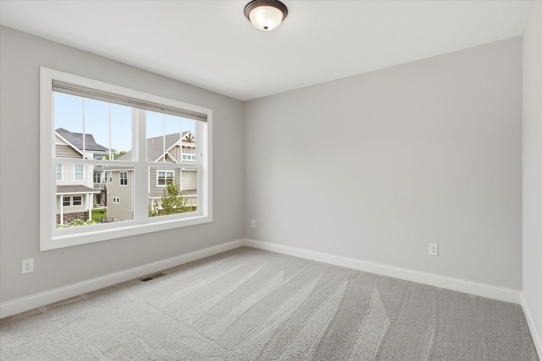 Bedroom #4 features a spacious layout, oversized window, and neutral finishes.