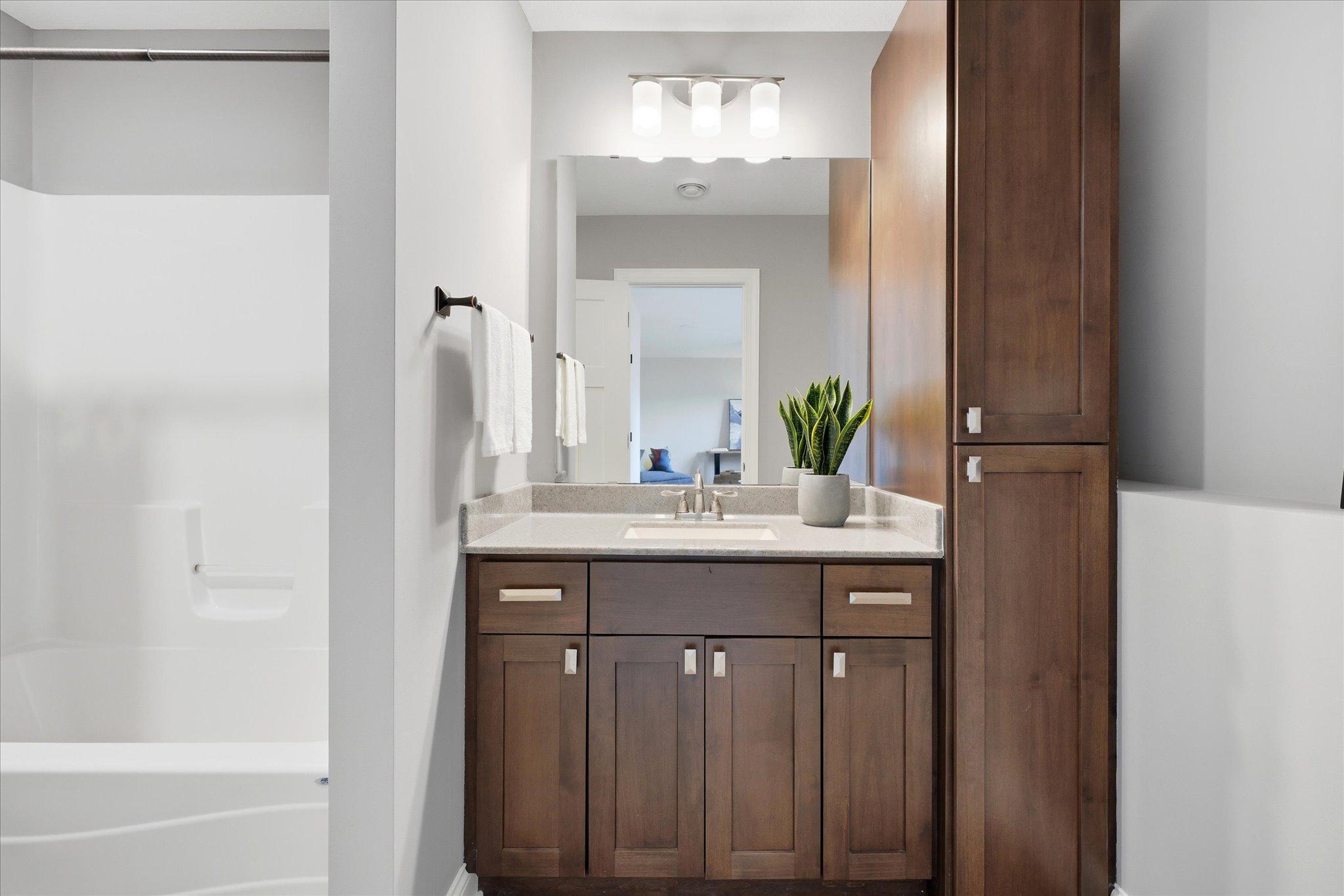 Convenient lower-level full bath features a spacious vanity with ample storage, a linen cabinet, durable luxury vinyl flooring, and a tub/shower combination.