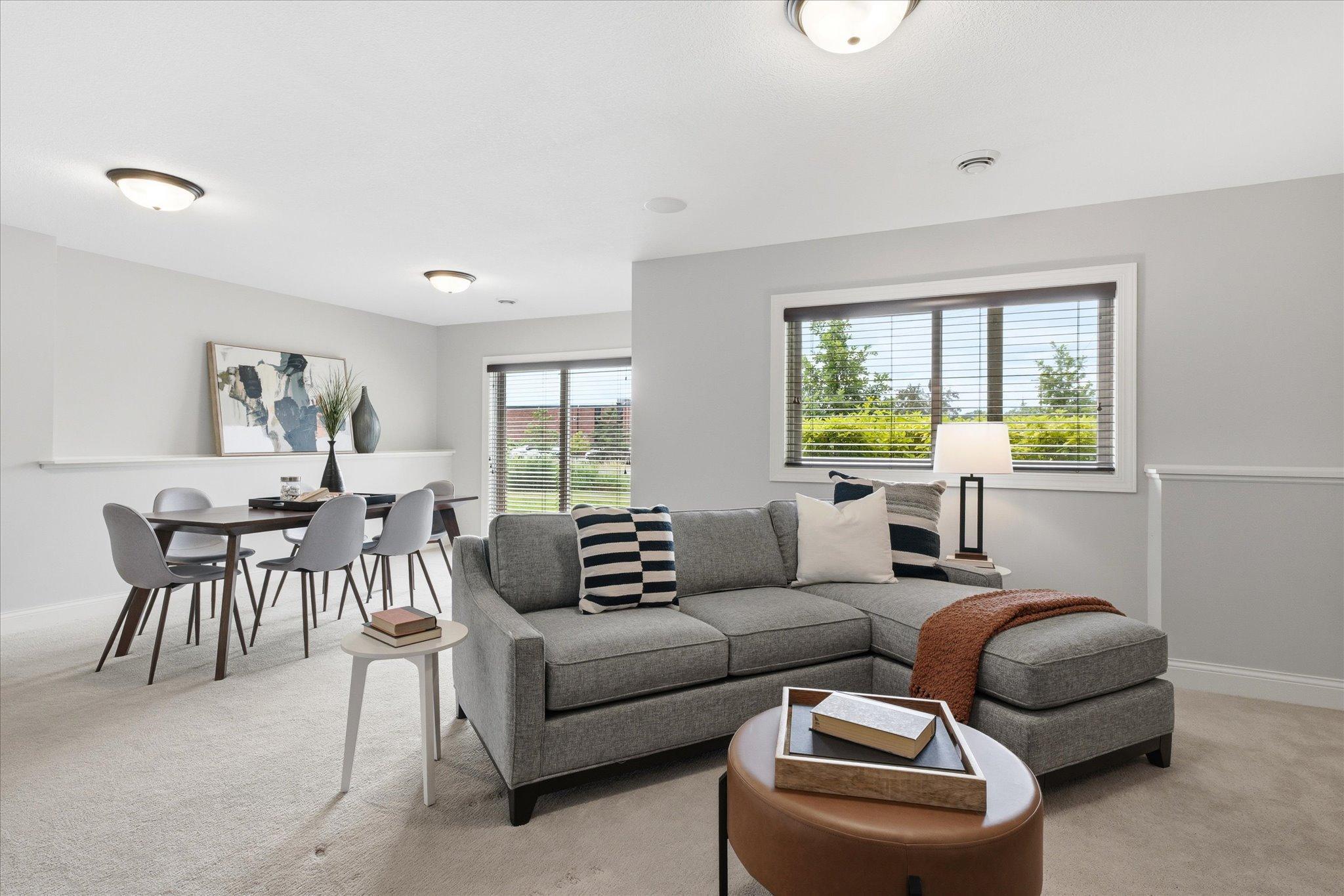Spacious lower-level family room offers the perfect place to relax or entertain, featuring large daylight windows, plush carpeting, and an open layout that flows seamlessly into the recreation area.