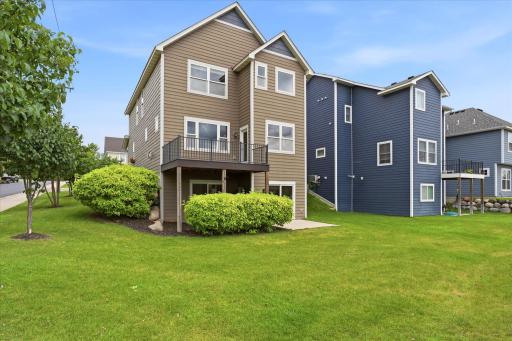 Beautiful rear elevation showcases the home's attractive curb appeal, maintenance-free exterior, spacious deck, walkout lower level, and professionally landscaped yard.