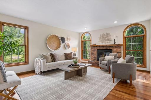 The family room offers a warm and welcoming retreat, anchored by a wood-burning fireplace and charming arched windows on either side.