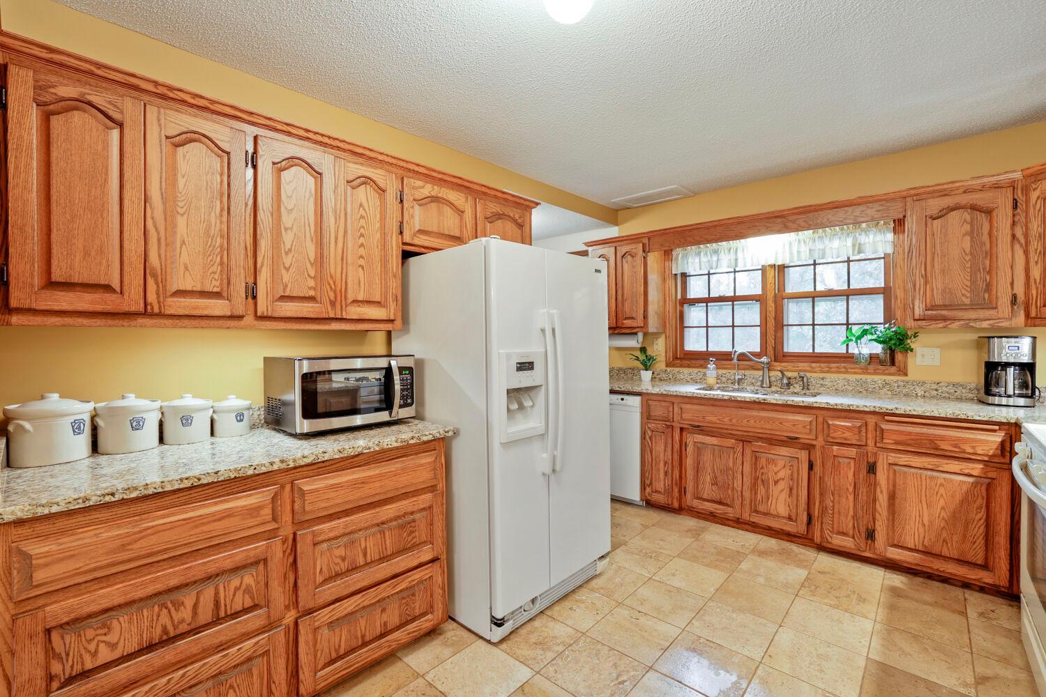 All oak kitchen cabinets with large storage drawers and granite counters.
