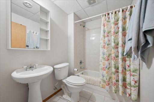 Full bath on the lower level with tile flooring and tub surround.