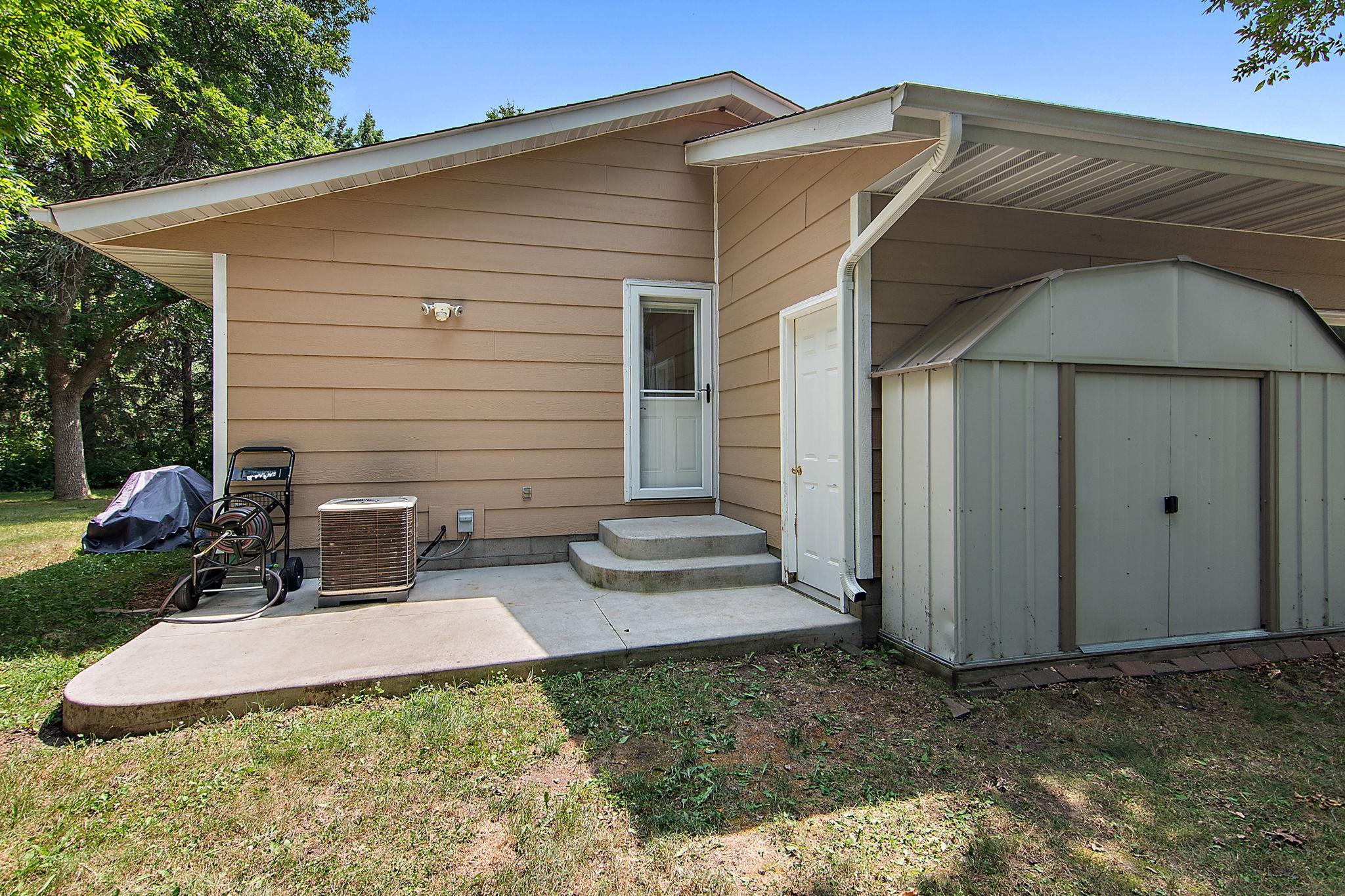 Side of home and another patio area and additional shed