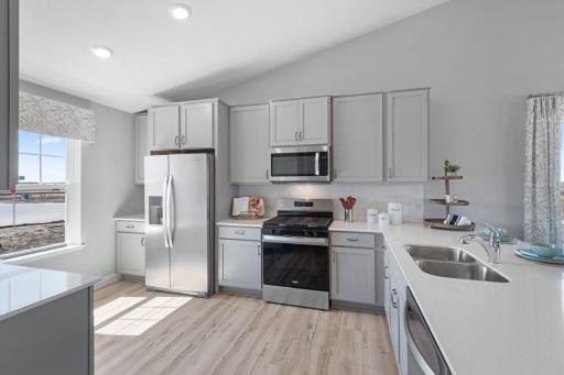Gorgeous kitchen with huge peninsula and pantry cabinet for storage. Stainless appliances, quartz counters, and subway backsplash! Photo of Model Home. Options and colors may vary. Ask Sales Agent for details.