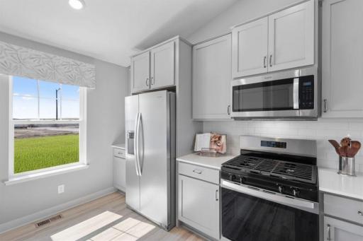 Kitchen shown with Willow (Light Gray) cabinets, gas oven/range, microwave over cooktop, and quartz countertops. Photos is of actual home. Colors and options may vary. Ask Sales Agent for details.