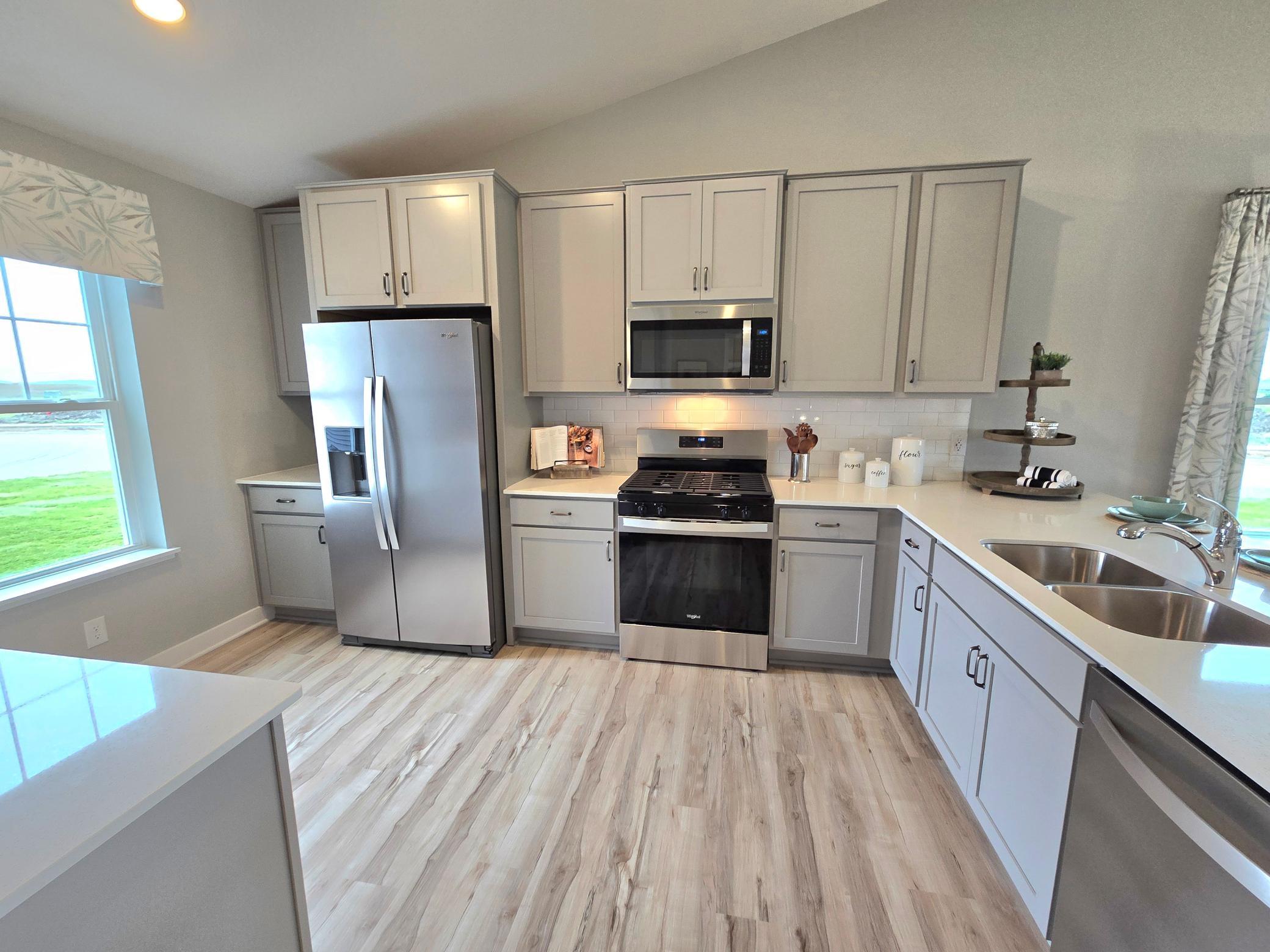 A true designer kitchen; Quartz countertops complimented by tile backsplash, a massive peninsula, plenty of cabinet space, plus a cabinet pantry! Photo is of actual home. Options and colors may vary. Ask Sales Agent for details.