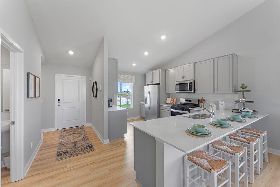 A true designer kitchen; Quartz countertops complimented by tile backsplash, a massive peninsula, plenty of cabinet space, plus a pantry cabinet! Photo is of model home. Options and colors may vary. Ask Sales Agent for details.
