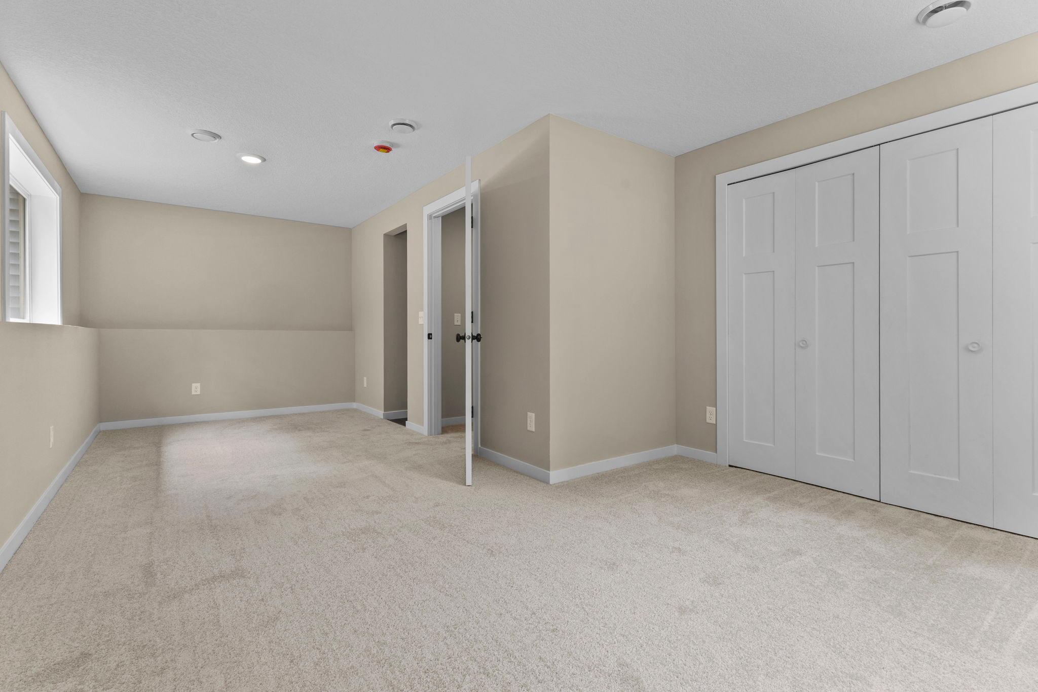 Lower-Level Primary Bedroom #3: A spacious private retreat with updated finishes, ample closet space, and a convenient three-quarter bathroom with shower, offering comfort and relaxation for everyday living.